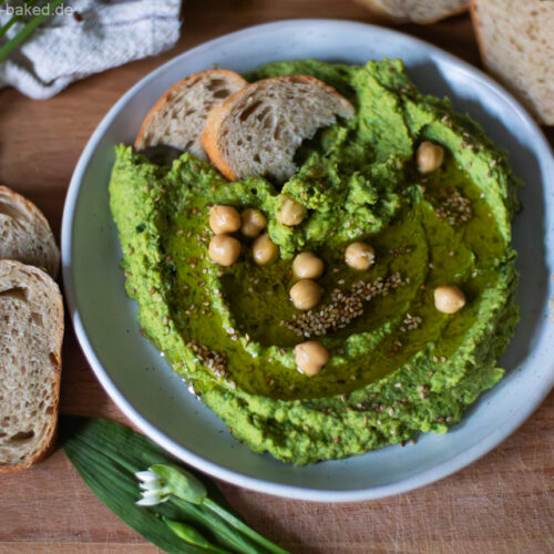 Brot wird in cremigen Bärlauchhummus gedippt – frischer Frühlingsaufstrich aus Kichererbsen und Bärlauch