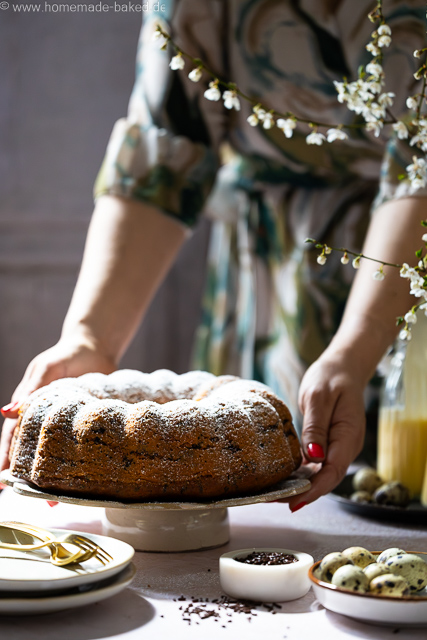 Saftiger Eierlikör-Gugelhupf mit Schokostreuseln auf einer Kuchenplatte, wird gerade auf den Tisch gestellt