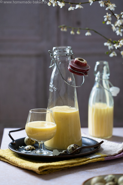Selbstgemachter Eierlikör mit ganzen Eiern aus dem Thermomix in zwei Flaschen und einem Glas. Das Glas und eine Flasche auf einem Tablett