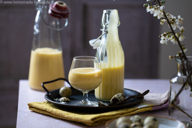 Selbstgemachter Eierlikör mit ganzen Eiern aus dem Thermomix in zwei Flaschen und einem Glas. Das Glas und eine Flasche auf einem Tablett