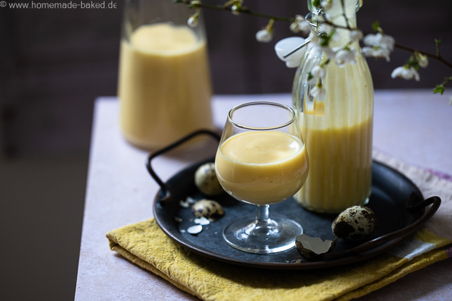 Selbstgemachter Eierlikör mit ganzen Eiern aus dem Thermomix in zwei Flaschen und einem Glas. Das Glas und eine Flasche auf einem Tablett