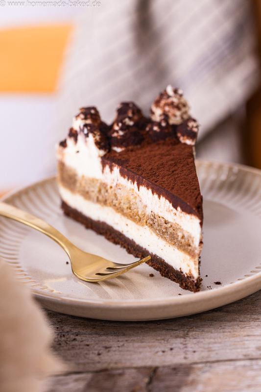 Stück No Bake Tiramisu Käsekuchen mit Kaffee, Mascarpone und Kakao auf einem Teller, mit einer Kuchengabel daneben