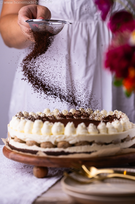 No Bake Tiramisu Cheesecake wird gerade mit Kakao bestäubt
