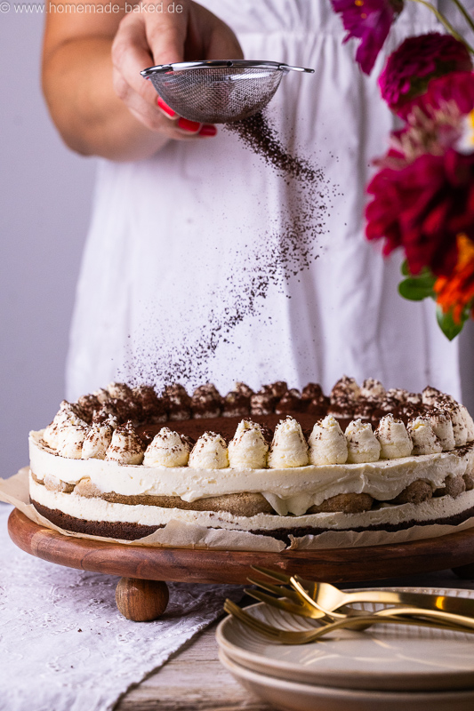 No Bake Tiramisu Cheesecake wird gerade mit Kakao bestäubt