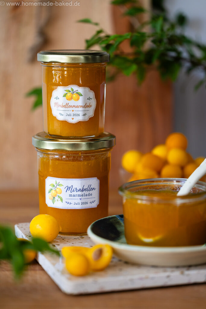 Zwei gestapelte Gläser Mirabellenmarmelade mit Vanille, davor ein frisch geöffnetes Marmeladenglas