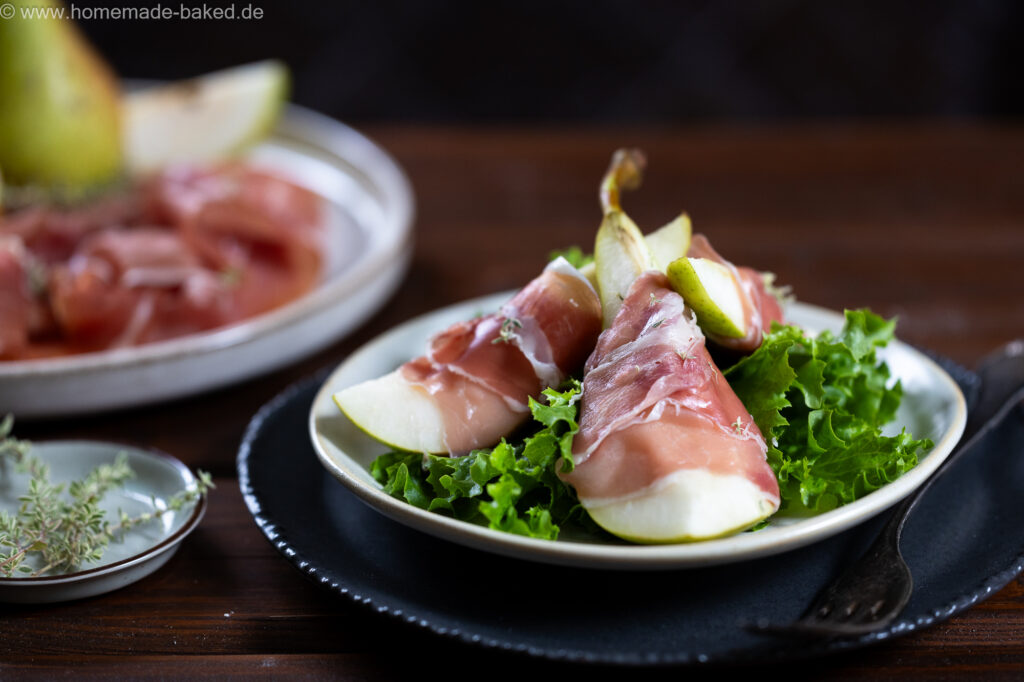 Parmaschinken mit Birne, auf einem Salatbett.