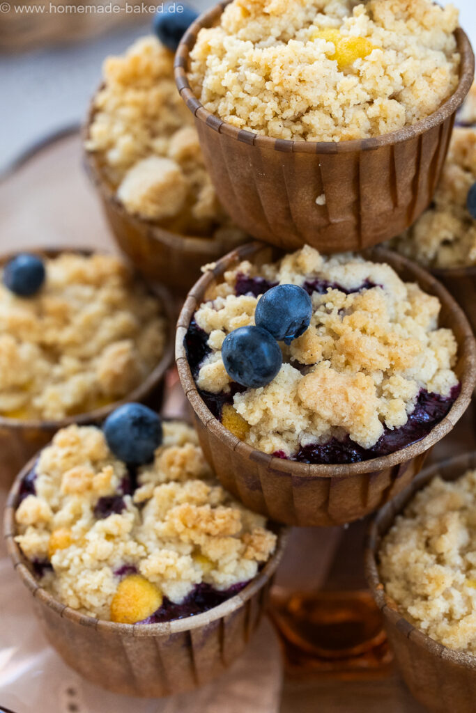 thermomix streuselmuffins zu einer pyramide gestapelt und mit heidelbeeren dekoriert.