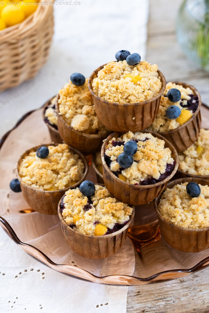 thermomix streuselmuffins zu einer pyramide gestapelt und mit heidelbeeren dekoriert.