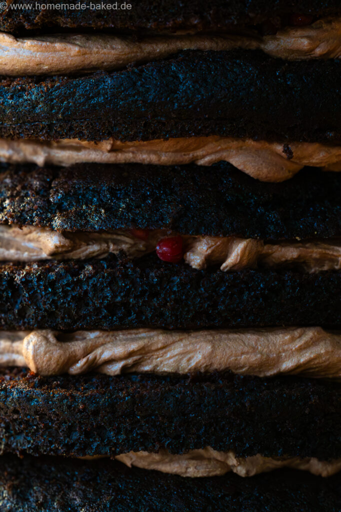 Nahaufnahme einer gerade gefüllten veganen Torte: Schokotorte mit Schokoganache und Himbeeren