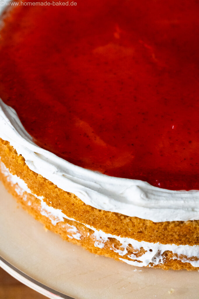 vegane Torte beim Füllen mit Frischkäse-Sahnecreme und frisch gekochter Erdbeermarmelade