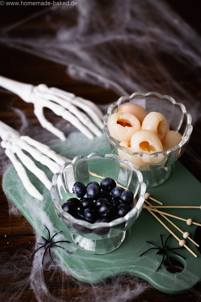 Halloween-Deko für Drinks, eine Schale mit Heidelbeeren, eine Schale mit Litschi aus der Dose