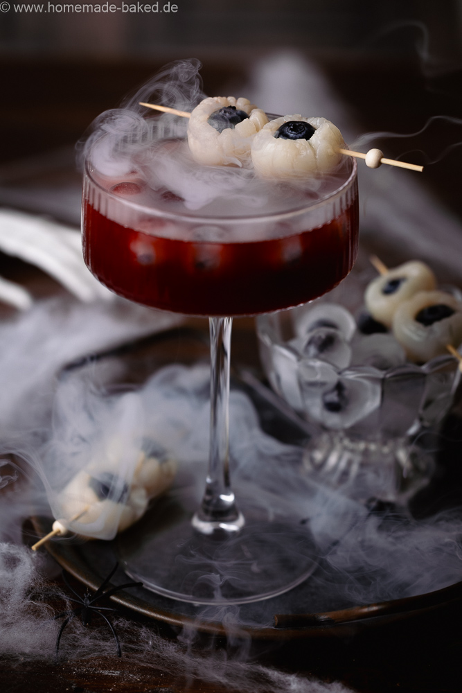 alkoholfreier halloween drink mit Augapfel-Deko, bestehend aus Litschi und heidelbeeren.