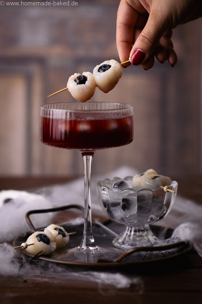 alkoholfreier halloween drink mit Augapfel-Deko, bestehend aus Litschi und heidelbeeren.