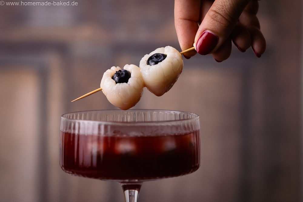 Augapfel-Deko für Halloween Drinks, bestehend aus Litschi und Heidelbeeren, zwei davon auf einem Spieß