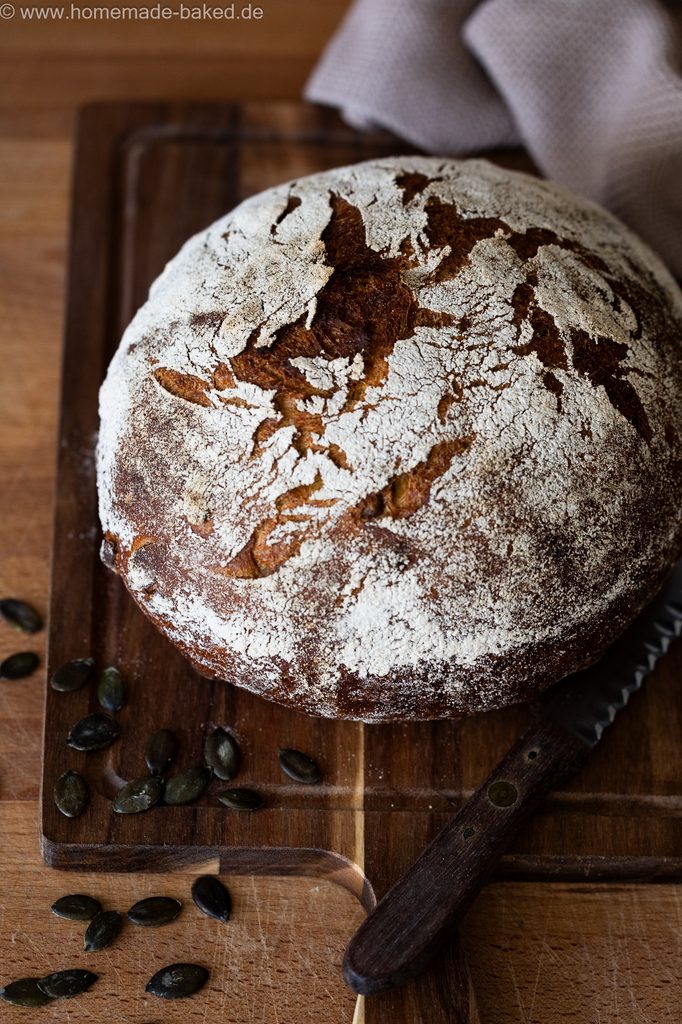 Rustikales Kürbis-Sauerteigbrot im Ganzen auf einem Brett fotografiert