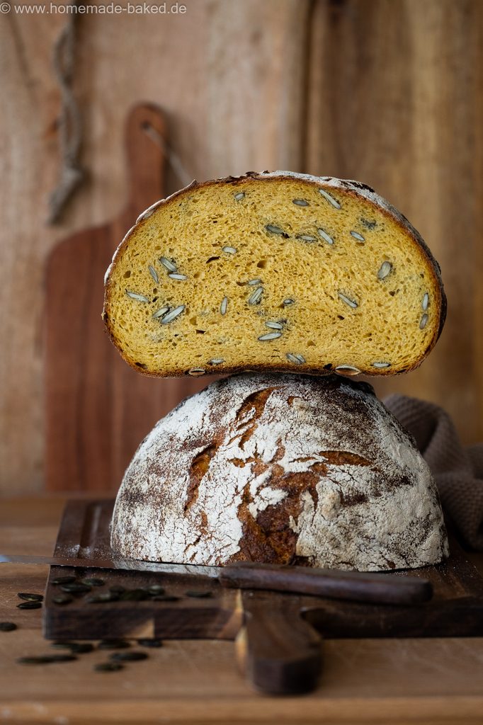 Kürbis-Sauerteigbrot mit Kürbiskerne, in der Mitte aufgeschnitten und gestapelt, so dass die saftige Krume und die Kruste gleichzeitig zu sehen sind.
