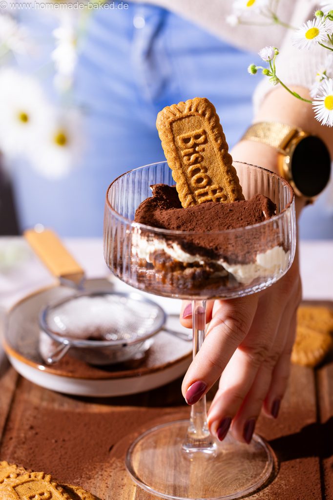 Lotus Biscoff Tiramisu im Glas, in einem hohen Champagnerkelch serviert, eine Hand greift danach.