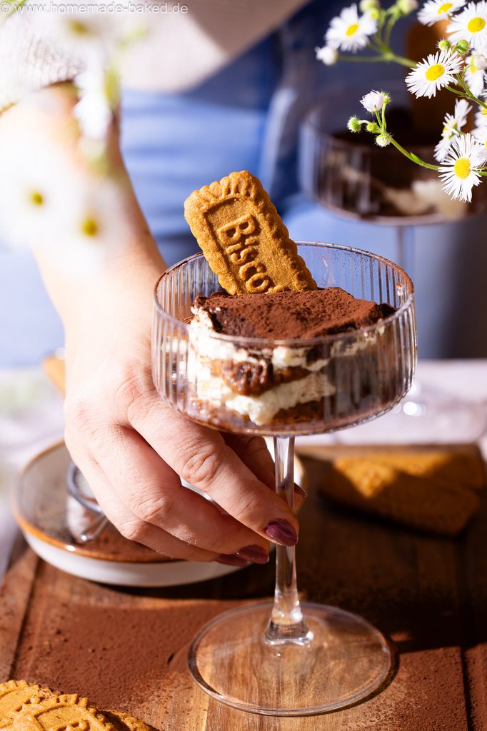 Lotus Biscoff Tiramisu im Glas, in einem hohen Champagnerkelch serviert, eine Hand greift danach.